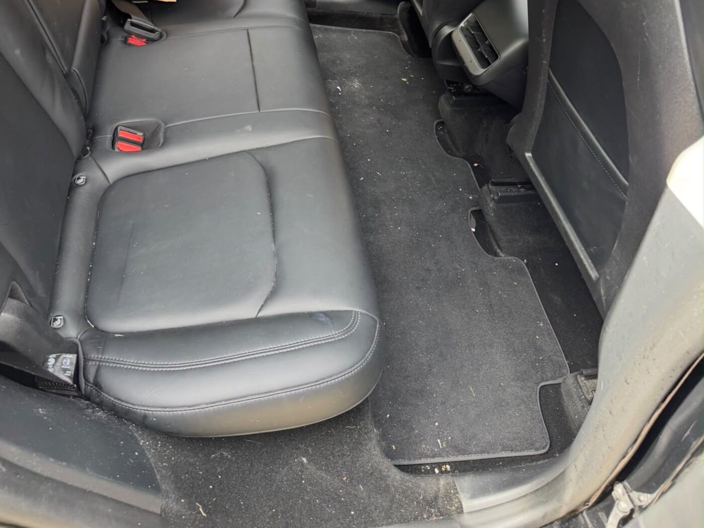 Rear seats and footwell before cleaning — debris and dust on the mats